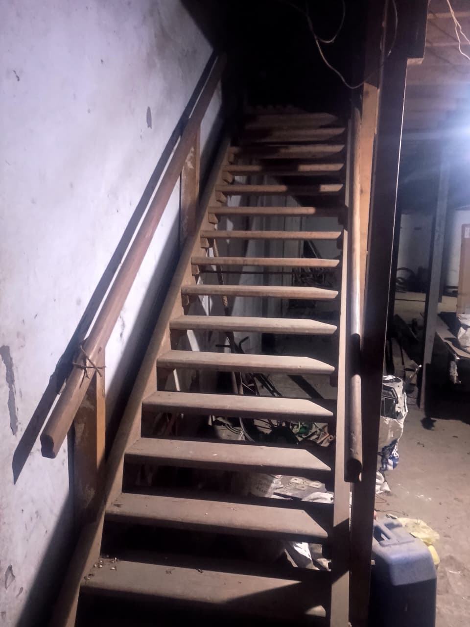 Open-tread wooden staircase with storage equipment underneath