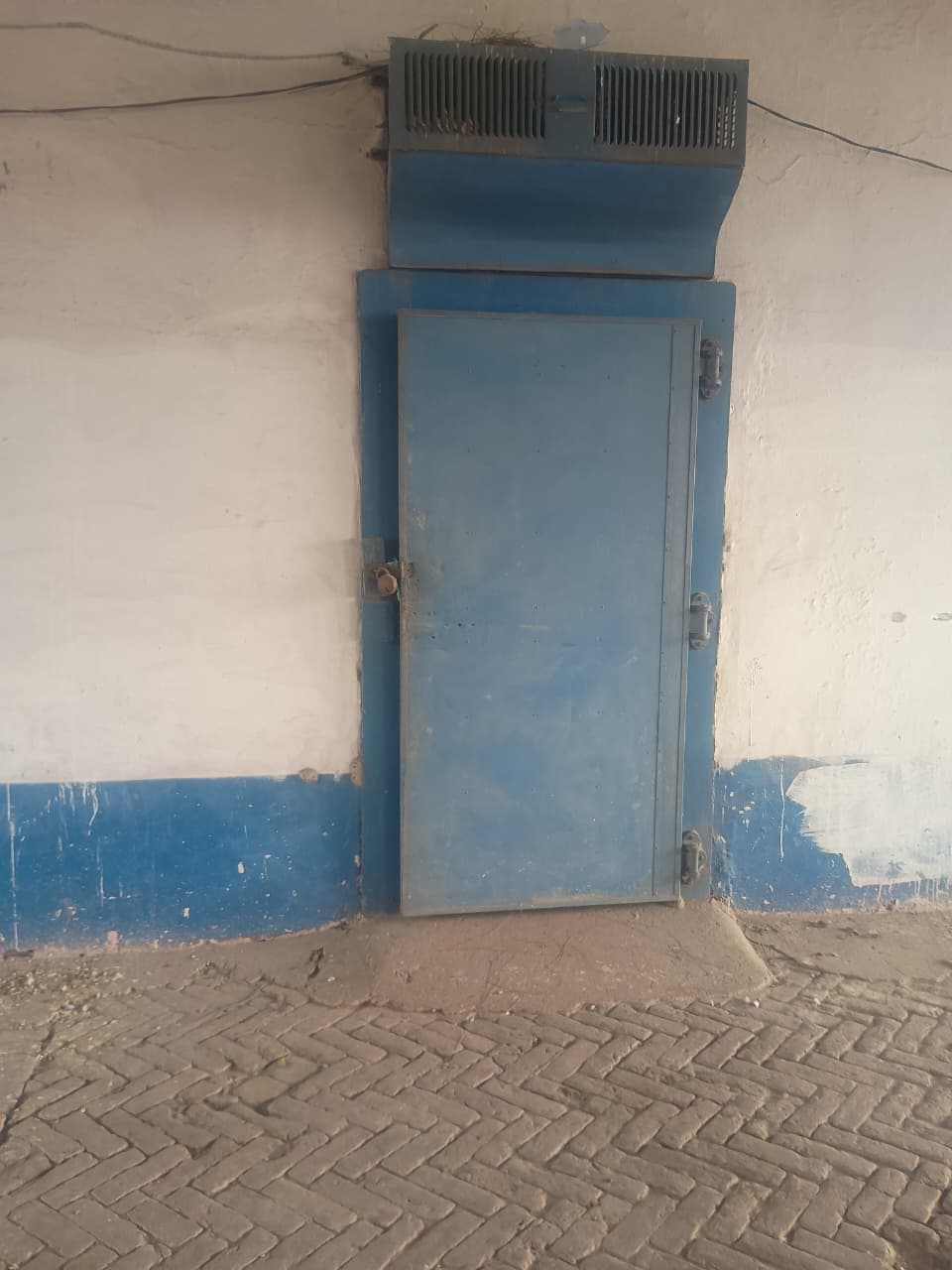 Blue cold storage door with air conditioning unit above — pre-cooling zone